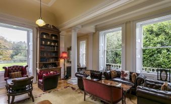 a large room with high ceilings , multiple windows , and a bookshelf filled with books , creating a cozy and inviting atmosphere at Doxford Hall Hotel and Spa