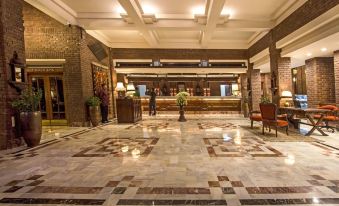 a large hotel lobby with marble floors , a reception desk , and several chairs arranged around the area at Faisalabad Serena Hotel