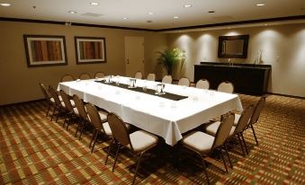 a large conference room with a long table surrounded by chairs and a long white tablecloth at Wyndham Minneapolis South/Burnsville