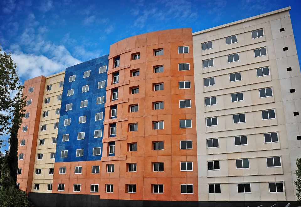 a building with orange , blue , and white exterior siding is shown against a blue sky at Courtyard Toluca Tollocan