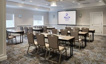 a conference room with chairs arranged in rows and a projection screen on the wall at Delta Hotels Basking Ridge