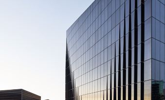 a modern building with large windows and a modern glass exterior , surrounded by a parking lot at Vibe Hotel Melbourne Docklands