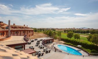 a large outdoor pool area with multiple lounge chairs and umbrellas , surrounded by a resort and golf course at Exe Layos Golf
