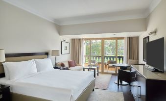 a hotel room with a king - sized bed , a flat - screen tv , and a balcony overlooking a golf course at Marriott Mena House, Cairo