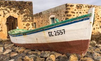 "a boat with the number "" cl 2 5 5 7 "" on it is resting in a rocky area next to a stone wall" at Hotel Rural Restaurante Mahoh