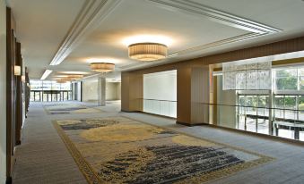 a long hallway with a carpeted floor and two chandeliers hanging from the ceiling at Sheraton Valley Forge King of Prussia