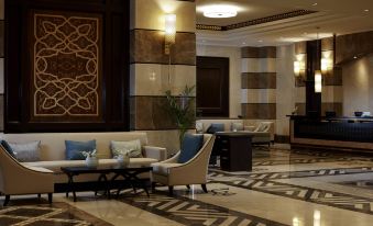 a large , well - lit hotel lobby with various seating arrangements and furniture , including couches , chairs , and a coffee table at Pullman Zamzam Madina