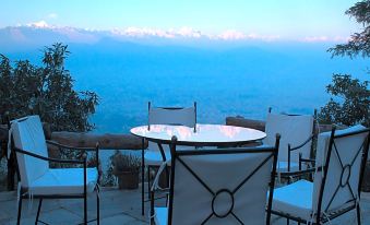 There is a table and chairs on the terrace, with mountains in the background during dusk or twilight at Haatiban Resort