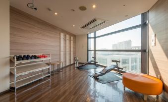 a modern home gym with large windows , wooden flooring , and various exercise equipment such as treadmills and weight machines at HOTEL MYSTAYS Utsunomiya