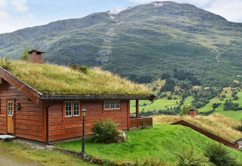 a small wooden house with a grass - covered roof is situated on a hillside , overlooking a valley at Olden