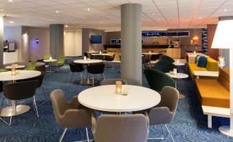 a modern restaurant with multiple dining tables and chairs , as well as a bar area at Novotel Maastricht