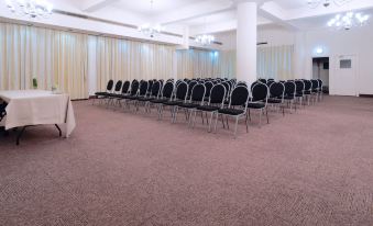 a large , empty conference room with rows of chairs and tables set up for a meeting or event at Albany Hotel