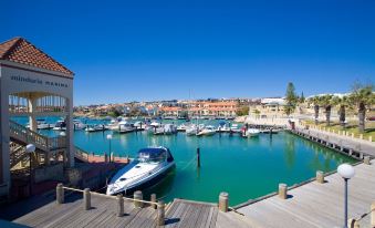 a marina with several boats docked , some of which are docked in the water and others floating on the water at The Marina Hotel - Mindarie