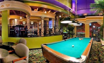 a pool table in a dimly lit room with green walls and purple ceiling , surrounded by other furniture at Red Lion Inn and Suites Victoria