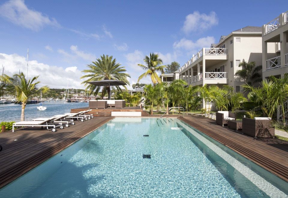 a large swimming pool with a view of the ocean and surrounding buildings , surrounded by palm trees at South Point Antigua