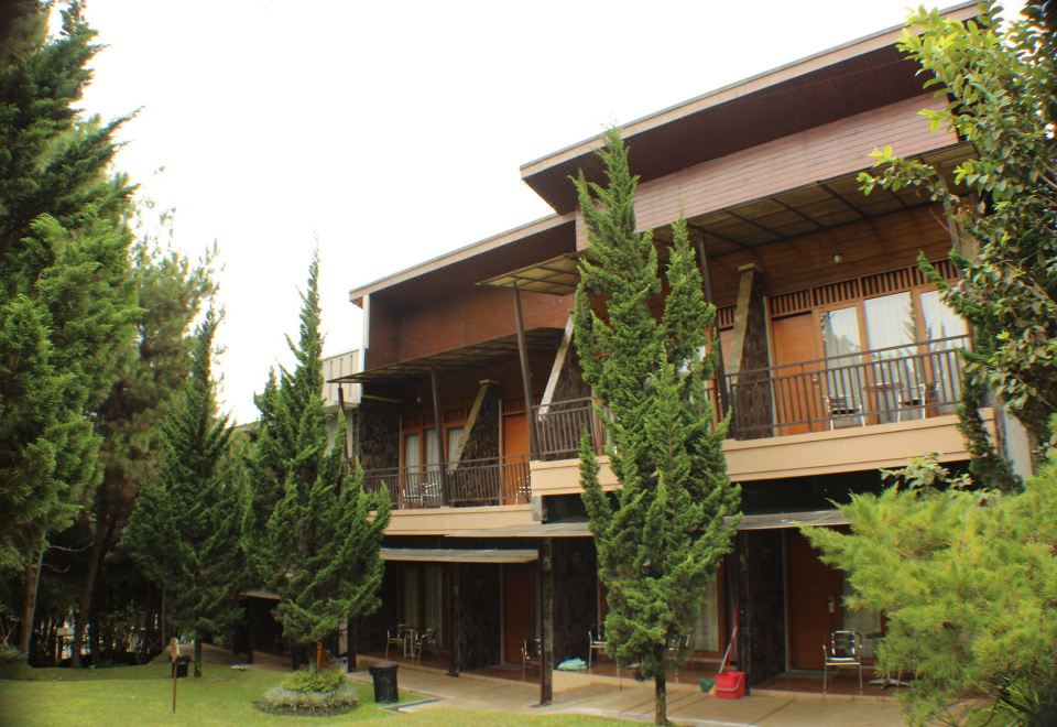 a two - story house surrounded by trees , with a balcony on the second floor of the building at Horison Green Forest Bandung