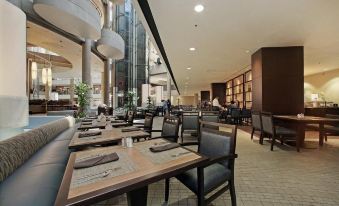 a large , well - lit restaurant with multiple dining tables and chairs , as well as a library - like setting at The Westin Bonaventure Hotel & Suites, Los Angeles