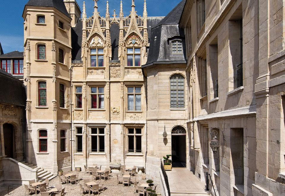 a courtyard surrounded by stone buildings , with several tables and chairs placed throughout the area at Hotel de Bourgtheroulde, Autograph Collection