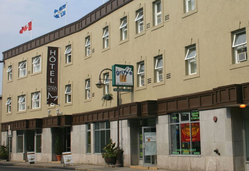 a building with a sign for a hotel and a flag flying in front of it at Hotel du Nord