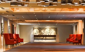a large hotel lobby with red chairs and couches , creating a comfortable seating area for guests at Doubletree by Hilton Montreal