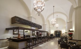 a large hotel lobby with a bar and dining area , featuring multiple chairs and tables at Parador de Leon - San Marcos