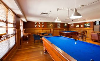 a pool table with blue felt is in a room with wooden walls and ceiling at Wilsonton Hotel