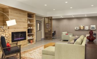 a modern living room with a fireplace , wooden shelves , and a couch , along with a dining table and chairs at Comfort Inn & Suites