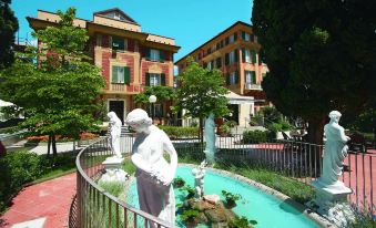 a courtyard with a fountain surrounded by a brick building , and several statues placed around the area at Hotel Le Palme