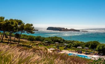 a beautiful beach with umbrellas and sun loungers , as well as a pool overlooking the ocean at Martinhal Sagres Beach Family Resort Hotel