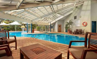 a large swimming pool with a glass ceiling and wooden lounge chairs next to it at Broadwater Resort Como