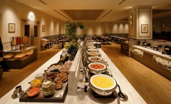 a long dining table filled with a variety of food items , including bowls , cups , and utensils at Hotel Monte Hermana Fukuoka