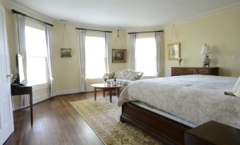 a large bedroom with hardwood floors , a large bed , and a couch in the corner at Woodville Bed and Breakfast