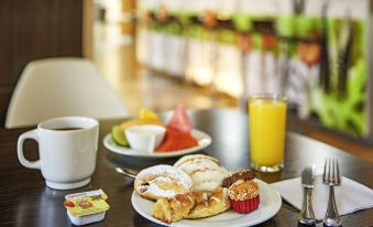 A table is set with plates, cups, and a choice of coffee or tea placed next to each plate at ibis Hong Kong Central and Sheung Wan Hotel