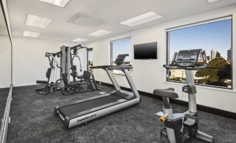 a well - equipped fitness room with various exercise equipment , including treadmills , weight machines , and a tv at Quest Kings Park