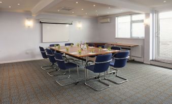 a conference room with a large table surrounded by blue chairs and a whiteboard on the wall at Holiday Inn Ipswich