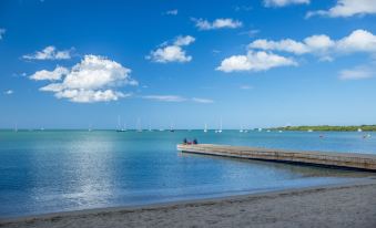 a serene beach scene with boats in the distance , clear blue water , and a few people on a pier at Aquarius Vacation Club at Boqueron Beach Resort