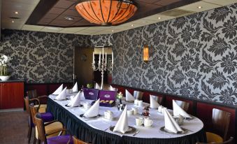 a long table with a white tablecloth and purple napkins is set up in a room with patterned walls at Fletcher Hotel - Restaurant Heiloo