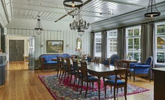 a large dining room with a wooden floor , blue couches , and a dining table surrounded by chairs at Fretheim Hotel