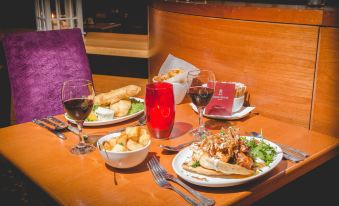 a wooden table is set with plates of food , glasses of wine , and a knife at Station House Hotel Letterkenny