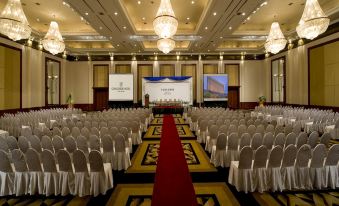 a large , well - lit conference room with white chairs and a red carpet , ready for an event at Concorde Hotel Shah Alam