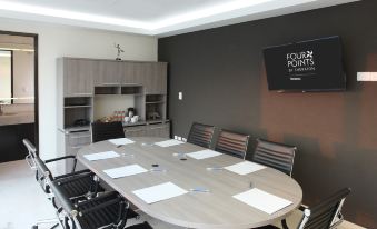 a conference room with a large wooden table , chairs , and a tv mounted on the wall at Four Points by Sheraton Veracruz