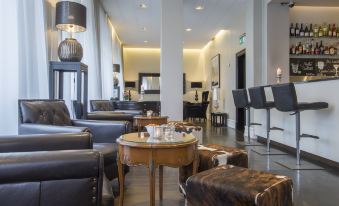 a modern living room with black leather chairs and ottomans , a round coffee table , and various decorative items at Radisson Blu 1919 Hotel Reykjavik
