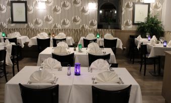 a well - decorated restaurant with several dining tables set for guests , each table having its own white tablecloth and purple napkins at Hob le Cheval Blanc