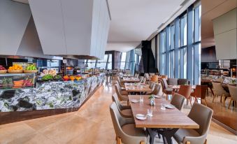 The restaurant features large windows and tables in the middle, complemented by an open concept living area at Element Kuala Lumpur