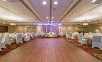a large conference room with white tables and chairs is set up for an event at Hotel Mtk Mount Kisco