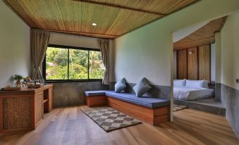 a cozy living room with wooden furniture , including a couch , chairs , and a dining table at Sai Daeng Resort
