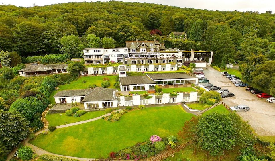 a large hotel with multiple buildings and greenery is surrounded by a green lawn and trees at Beech Hill Hotel & Spa