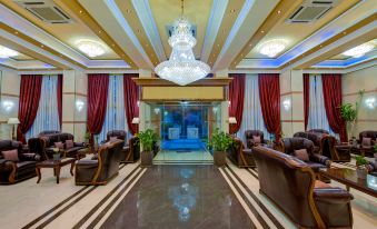 a luxurious hotel lobby with a large chandelier hanging from the ceiling , surrounded by multiple couches and chairs at Semeli Hotel