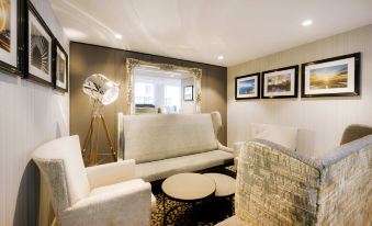 a modern living room with a white couch , coffee table , and chairs , surrounded by framed art on the walls at Sofitel London Gatwick