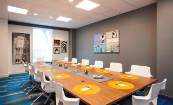 a conference room with a long wooden table , white chairs , and yellow place mats , set up for a meeting at Aloft Miami Dadeland